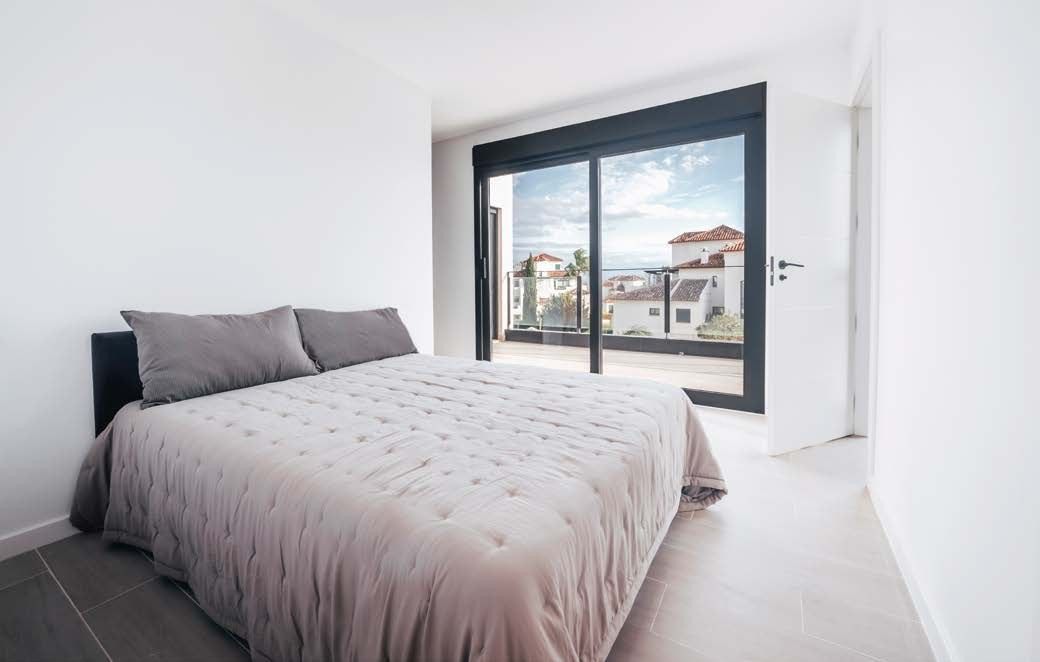 Dormitorio de la casa de Finestrat con ventanal corredizo de perfiles oscuros abierto a la terraza